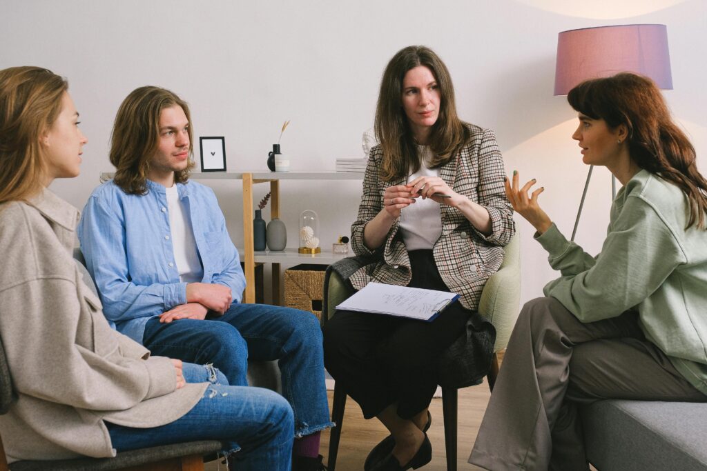 A group therapy session with three people, and a therapist. 