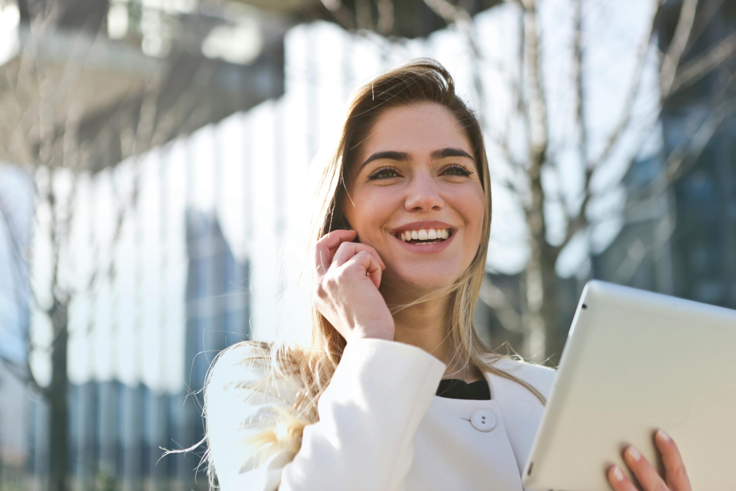 A woman smiling with an iPad in her hand.