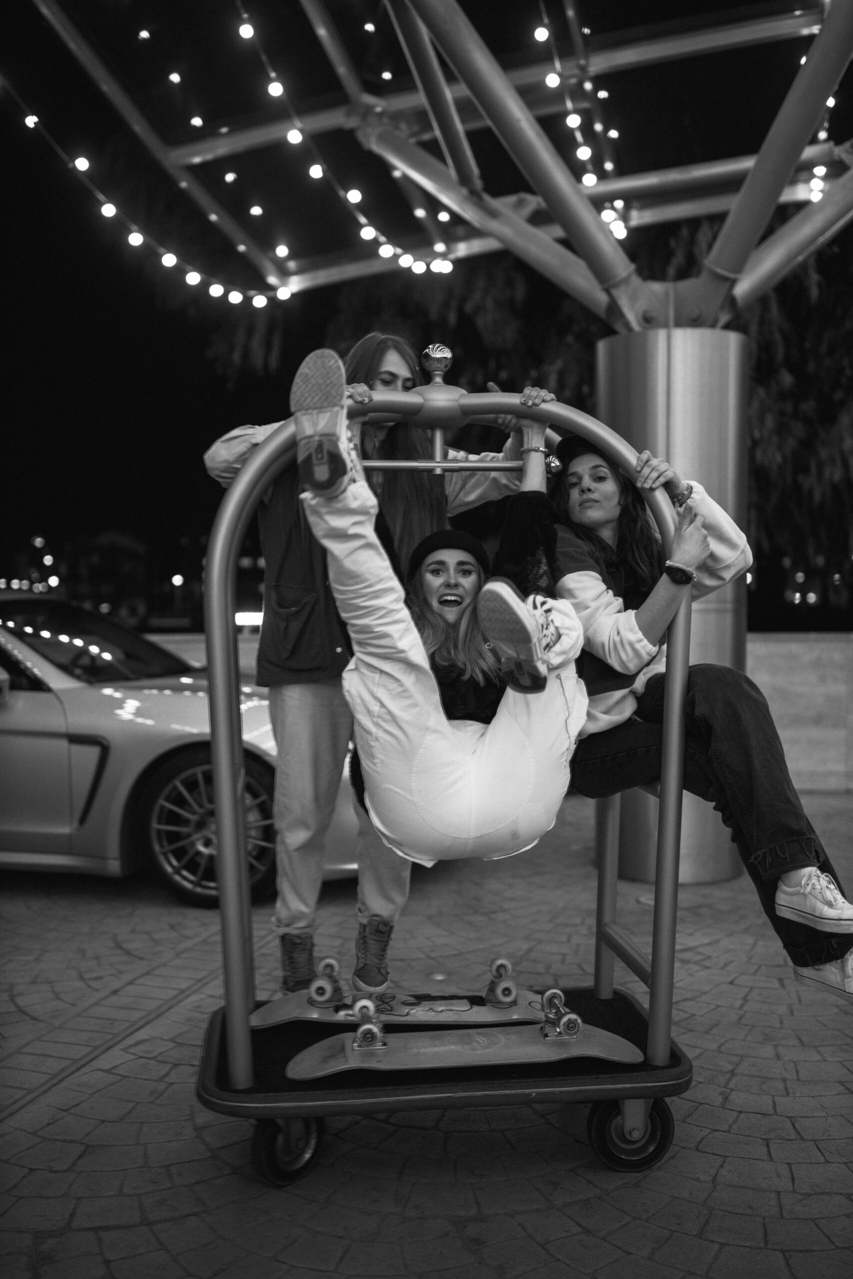 A woman hanging from a hotel luggage cart.