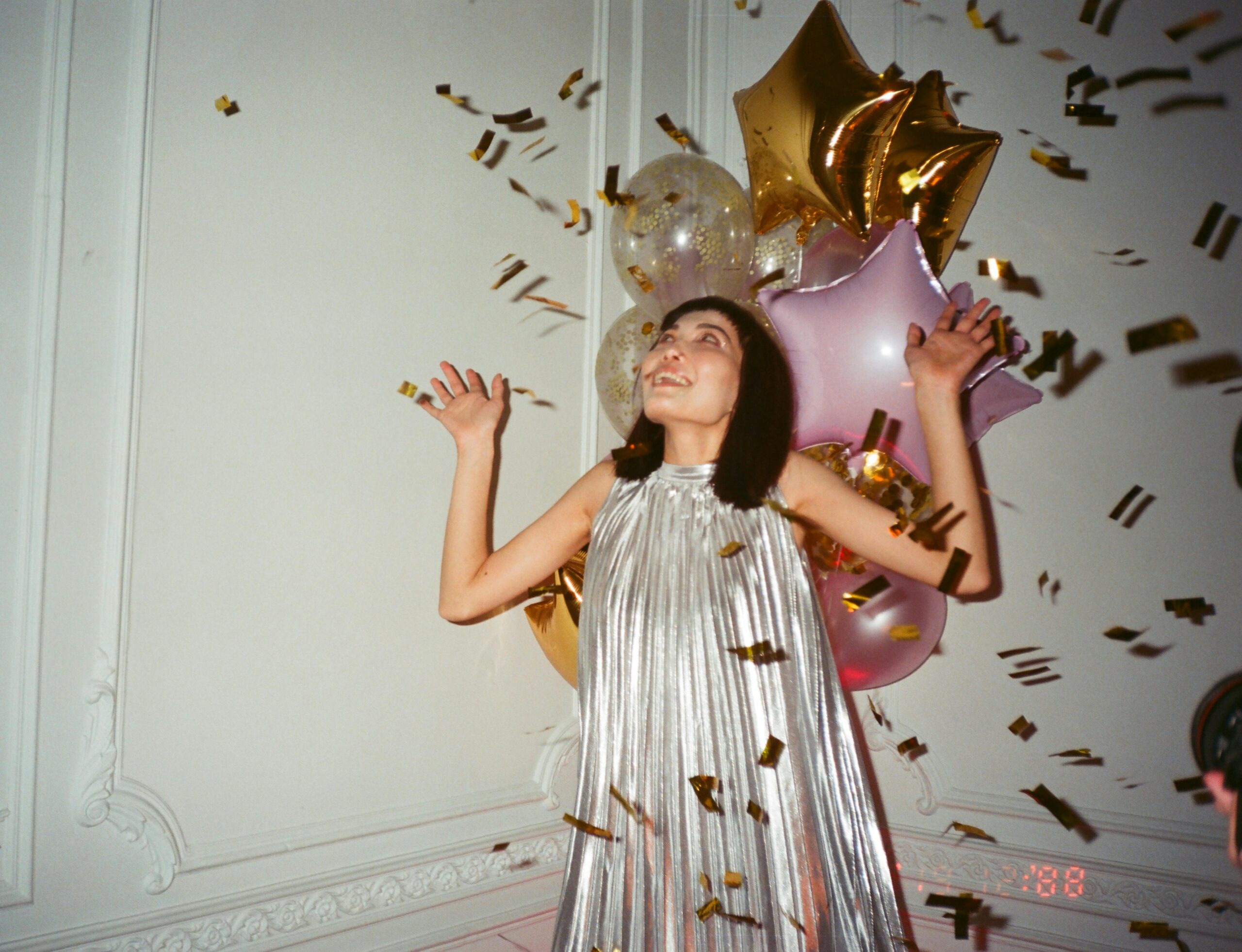 A woman at a party with confetti in the air around her.