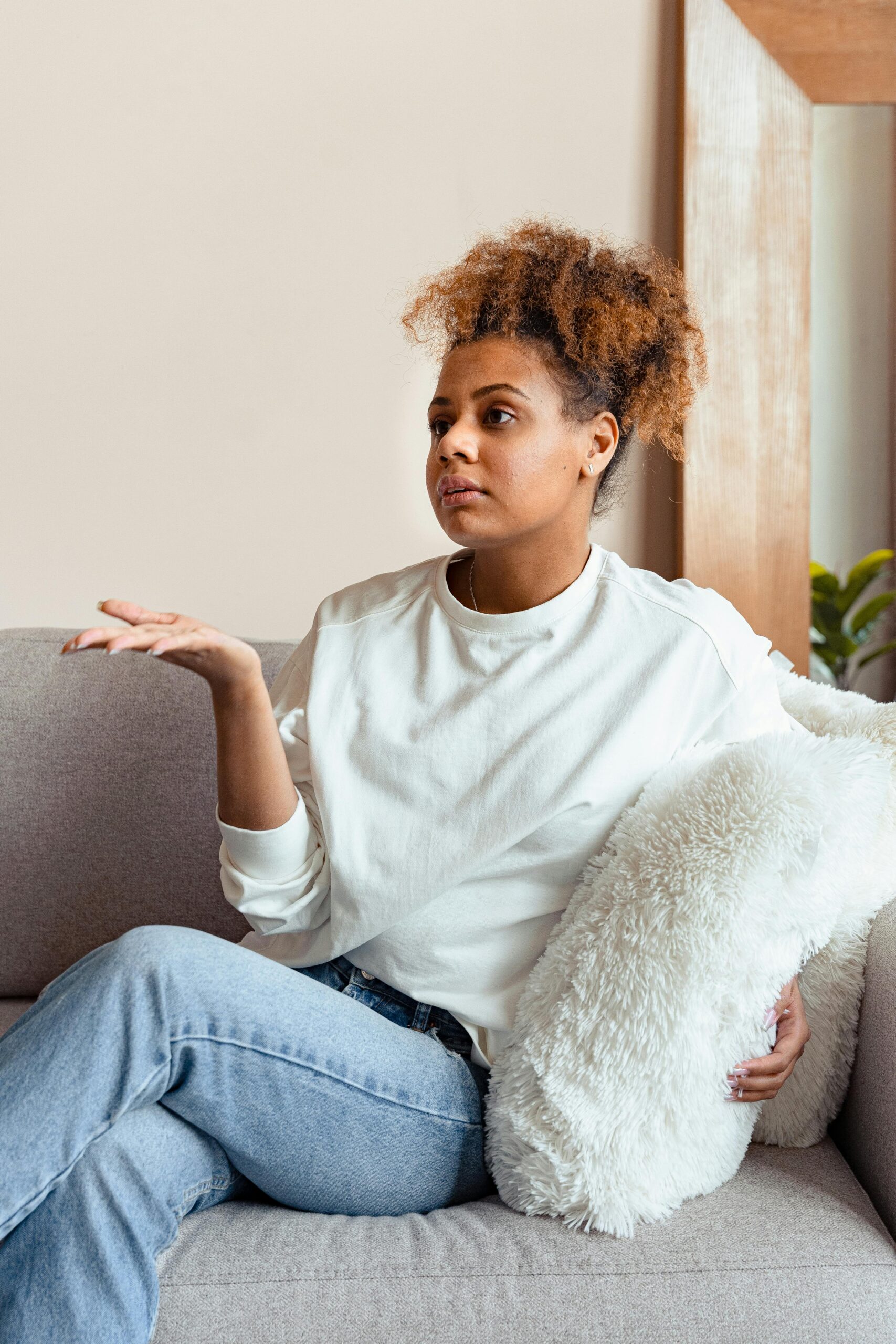 A woman sitting on a couch and talking with her hands.