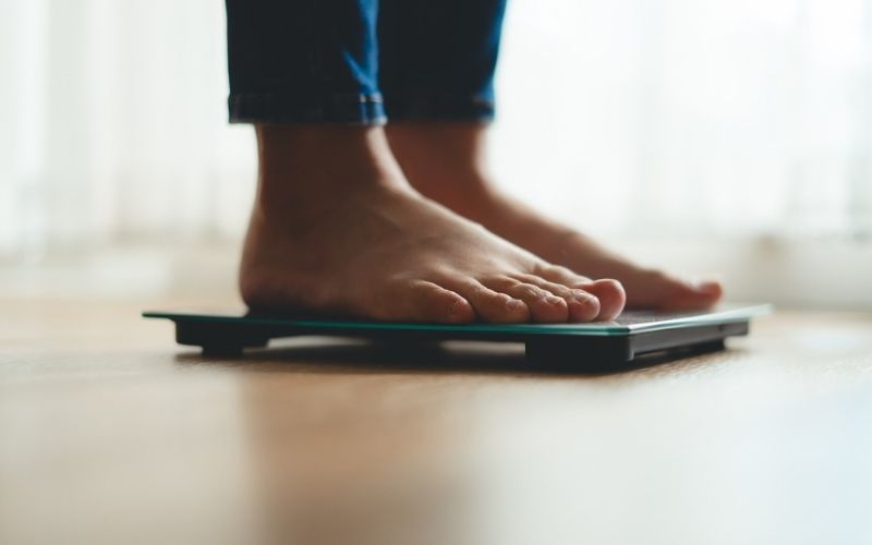 woman with an eating disorder standing on a scale