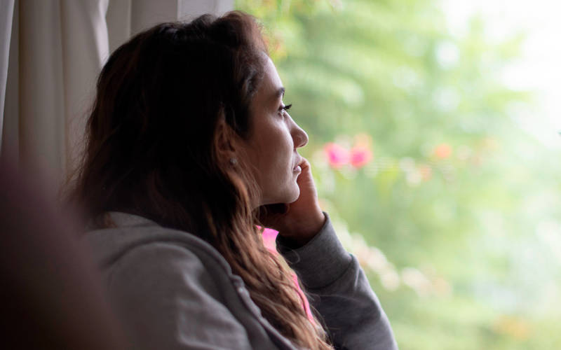 A woman looking outside of a window, contemplating addiction treatment at Luna Recovery for Women in North Andover, MA.