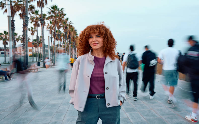 A woman standing in public, contemplating about the differences between occasional substance use and dependence.