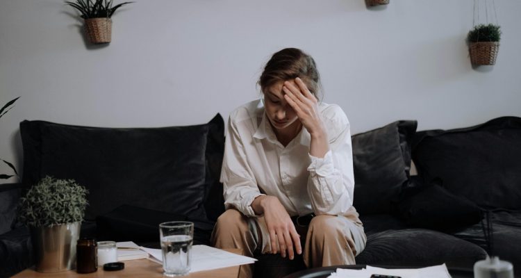 A stressed person sitting on the couch with their head in their hands.